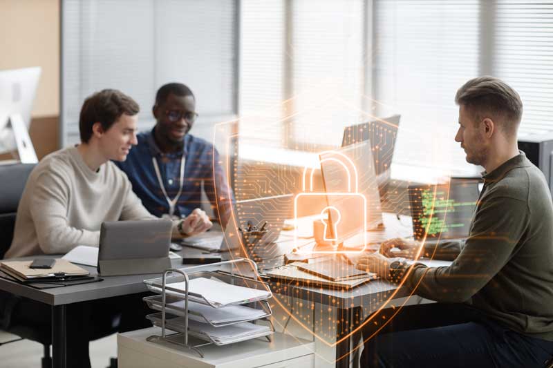 Wide shot of multi-ethnic male IT team working on new cyber security project while sitting at desks of modern company office.